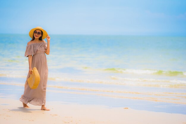 Paseo feliz de la sonrisa asiática joven hermosa de la mujer del retrato en el mar al aire libre tropical de la playa de la naturaleza