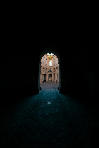 Pasillo oscuro con puerta de arco con vistas a un edificio de hormigón.