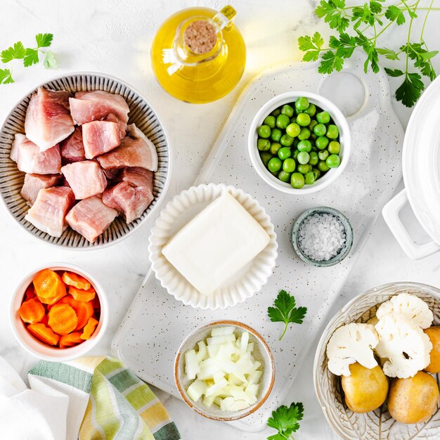 Paso 1 Receta de sopa con albóndigas, coliflor, guisantes, zanahorias y crema sobre un fondo blanco Cuadrado