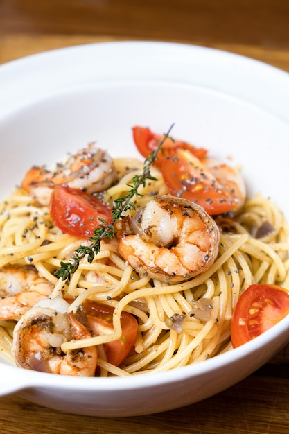 Pasta con camarones fritos y tomates frescos.