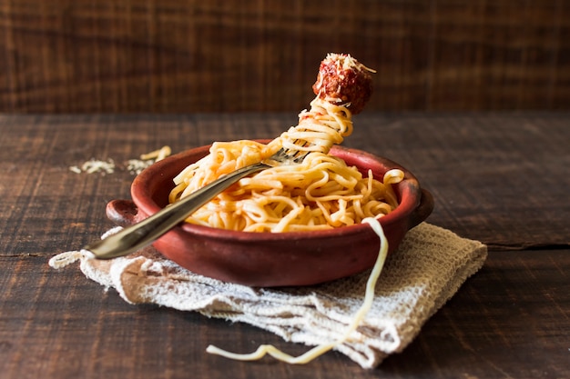 Pasta casera con albóndiga en loza sobre servilleta sobre mesa de madera