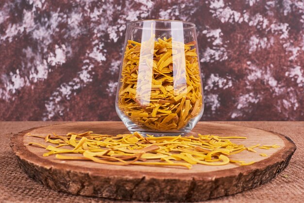 Pasta casera en un vaso y sobre la plancha de madera.