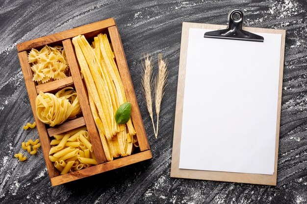 Pasta sin cocer en caja de madera con maqueta portapapeles