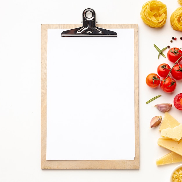 Foto gratuita pasta sin cocer e ingredientes con maqueta de portapapeles