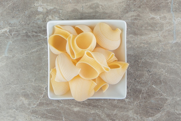 Pasta de conchiglie sin cocer en un tazón blanco.