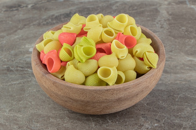 Foto gratuita pasta conchiglie cruda en tazón de madera