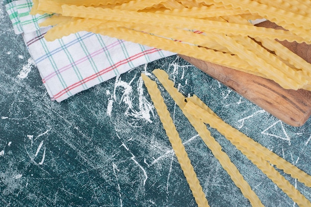 Pasta cruda amarilla con mantel en espacio azul.