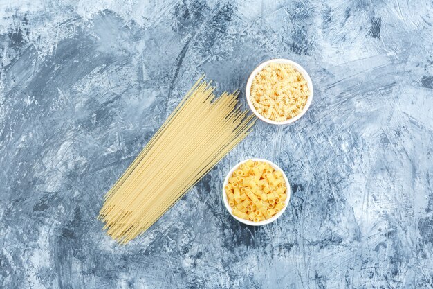 Pasta cruda en cuencos planos yacía sobre un fondo de yeso sucio