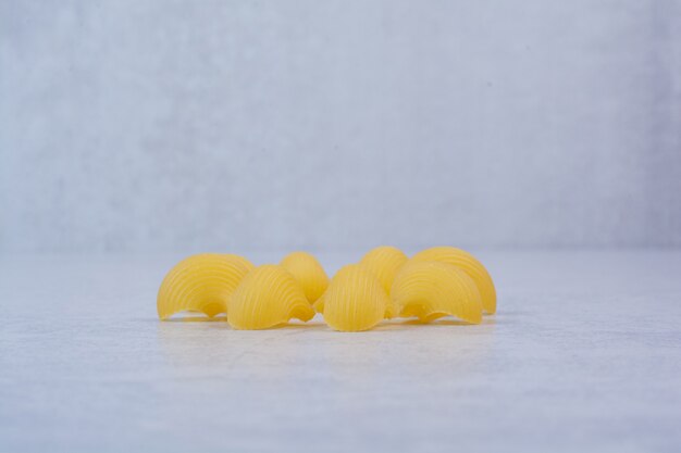 Pasta cruda con forma de concha sobre superficie blanca