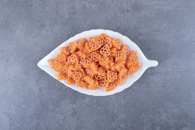 Pasta cruda en forma de corazón en un plato en forma de hoja.