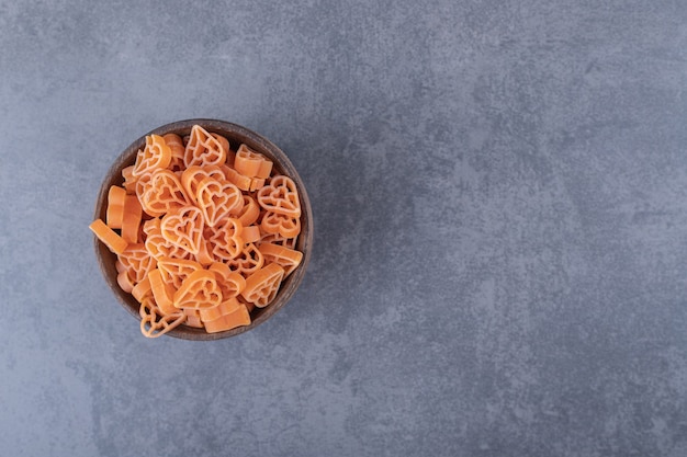 Pasta cruda en forma de corazón en un tazón de madera.