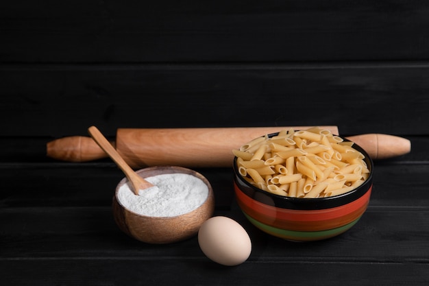 Pasta cruda con harina y huevo de gallina colocado sobre mesa de madera. Foto de alta calidad