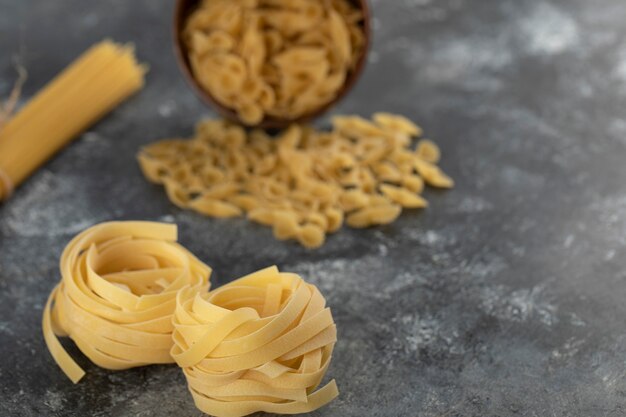 Pasta cruda nido seco en una pared de mármol.