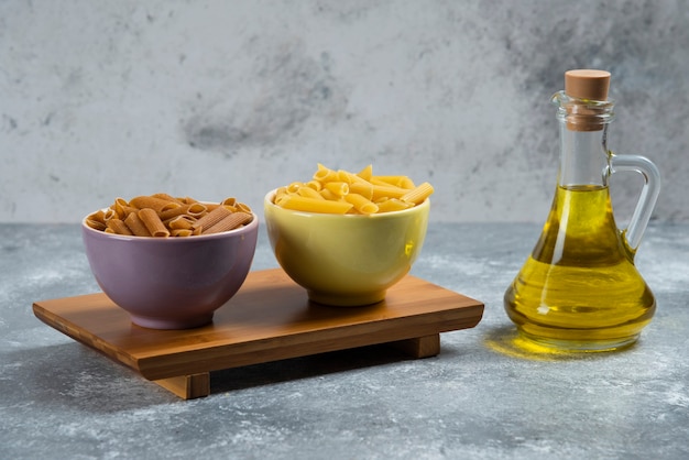 Foto gratuita pasta cruda de sémola amarilla y marrón con una botella de vidrio de aceite.