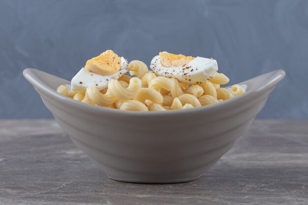 Pasta decorada con huevo cocido en cuenco de cerámica.