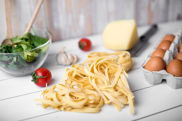 Pasta e ingredientes de tallarines crudos sobre mesa de madera