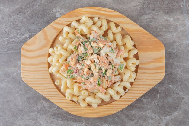 Pasta con ensalada fresca en placa de madera.