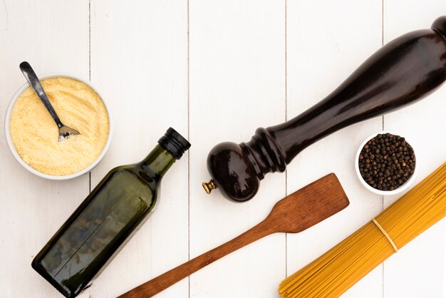 Pasta de espagueti cruda y su ingrediente con utensilio de cocina en mesa blanca