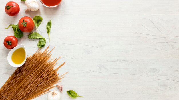 Pasta de espagueti e ingredientes frescos sobre mesa blanca