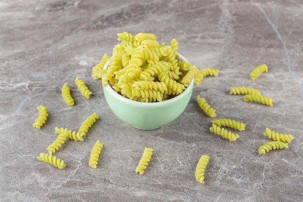 Pasta esparcida de un cuenco lleno, sobre la superficie de mármol.