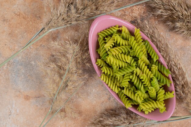 Foto gratuita pasta espiral verde sin preparar en un tazón rosa. foto de alta calidad