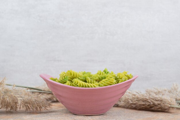 Foto gratuita pasta espiral verde sin preparar en un tazón rosa.