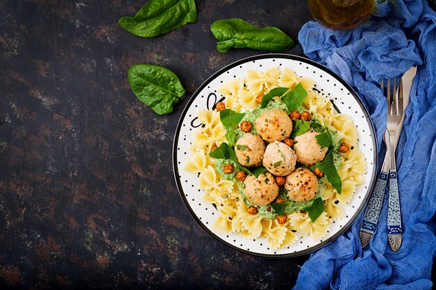 Pasta Farfalle con albóndigas y salsa de espinacas con garbanzos fritos.