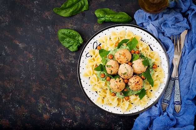 Pasta Farfalle con albóndigas y salsa de espinacas con garbanzos fritos.