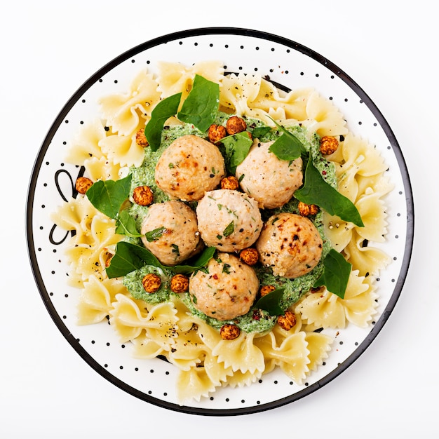 Pasta Farfalle con albóndigas y salsa de espinacas con garbanzos fritos.