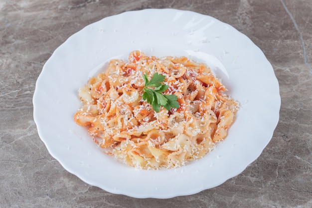 Pasta farfalle con boloñesa en el bol, sobre la superficie de mármol.