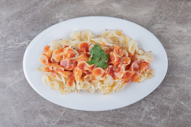 Pasta farfalle con boloñesa en el plato, sobre la superficie de mármol.