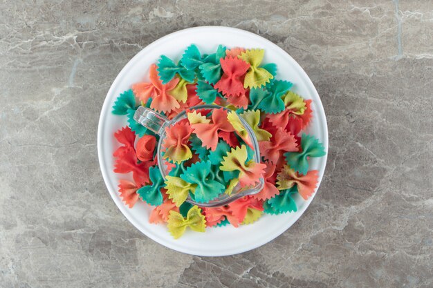 Pasta farfalle colorida en taza de vidrio.