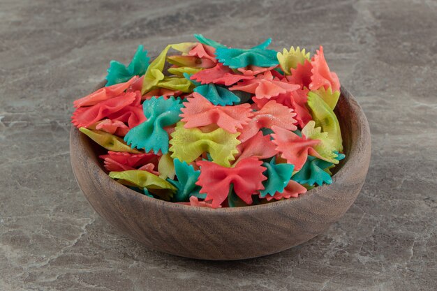 Pasta farfalle colorida en tazón de madera