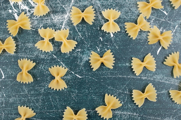 Pasta farfalle cruda esparcida sobre fondo azul. Foto de alta calidad