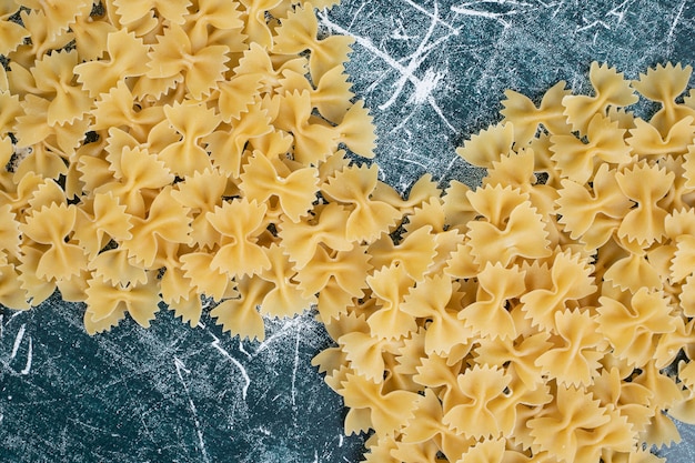 Pasta farfalle cruda formada como cinta sobre fondo azul. Foto de alta calidad