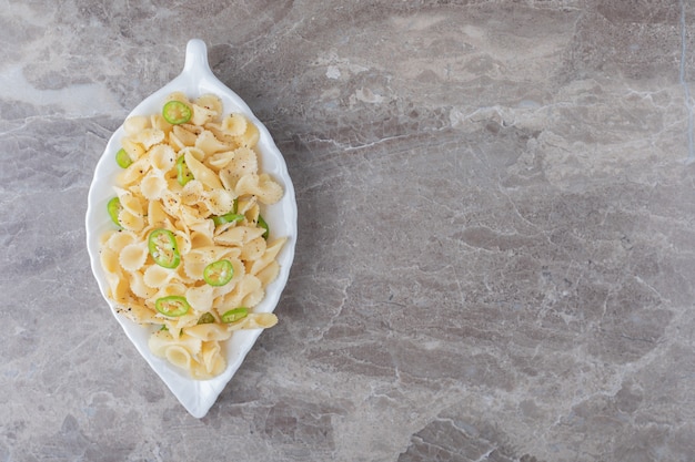 Pasta farfalle con pimienta en un plato elegante, sobre la superficie de mármol.