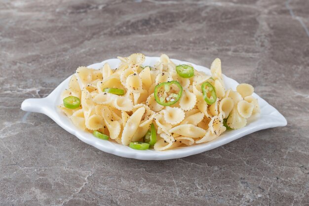 Pasta farfalle con pimienta en un plato elegante, sobre la superficie de mármol.