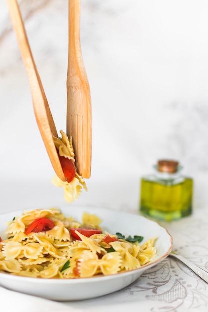 Pasta Farfalle recogida con cuchara de madera y espátula del plato