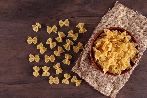 pasta farfalle sobre tela de saco en la superficie de madera vista superior