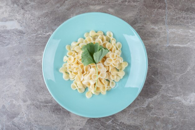 Pasta farfalle con verduras en el plato, en el mármol.