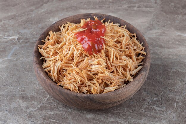 Pasta de fideos con salsa de tomate en el bol, sobre el mármol.