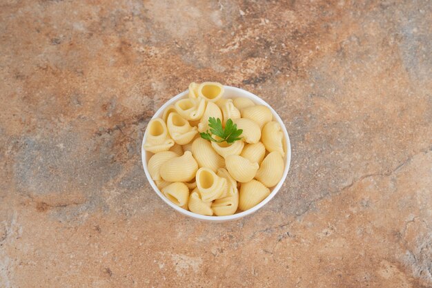 Pasta en forma de concha en un recipiente con perejil.