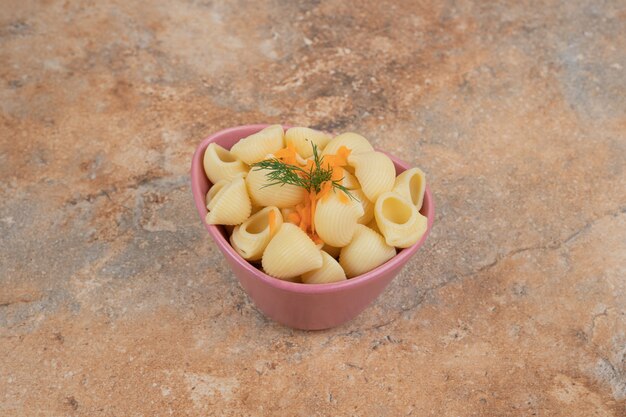 Pasta en forma de concha con rodajas de zanahoria y eneldo en un tazón