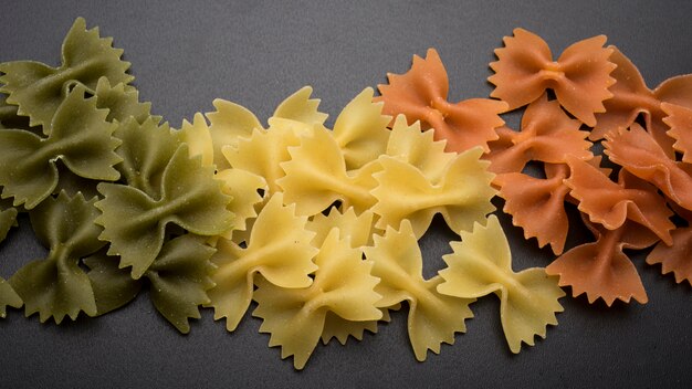 Pasta fresca de Farfalle en verde; Colores amarillo y naranja sobre encimera de cocina.