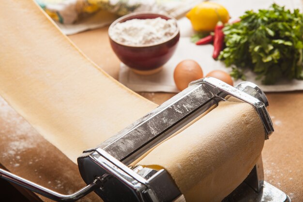 La pasta fresca y la máquina en la mesa de la cocina.