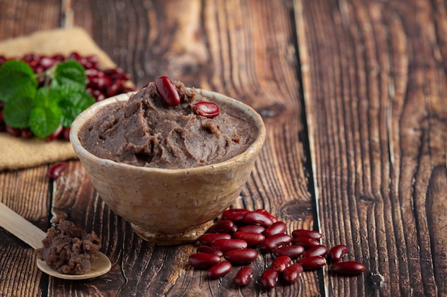 Pasta de frijoles rojos dulces en tazón blanco lugar sobre un piso de madera