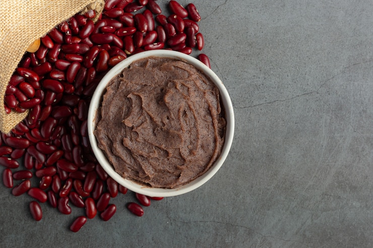 Foto gratuito pasta de frijoles rojos dulces en un tazón blanco lugar sobre un piso oscuro
