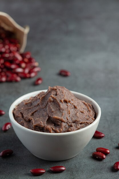 Pasta de frijoles rojos dulces en un tazón blanco lugar sobre un piso oscuro