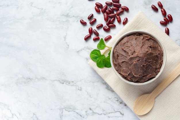 Pasta de frijoles rojos dulces en un tazón blanco sobre un piso de mármol blanco