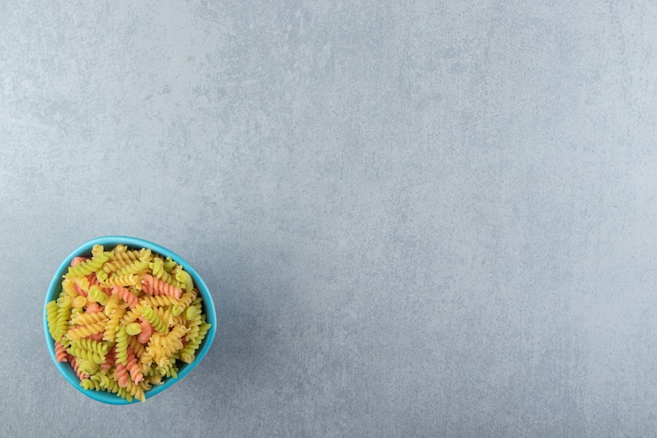 Foto gratuito pasta fusilli de colores en un tazón azul.